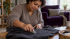 Hands gently removing pills from a knit sweater