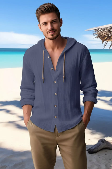 Man wearing a blue button-up shirt with a beach in the background
