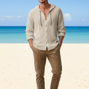 Man wearing a beige button-up shirt with a beach background
