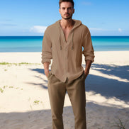 Man wearing a beige button-up shirt with a beach in the background