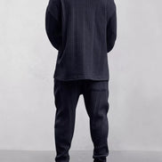 A person shown from the back wearing a dark navy cable-knit long-sleeve top and matching jogger pants, 