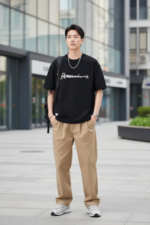 Person wearing a black t-shirt with a logo, standing against a plain background