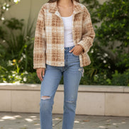 Woman wearing a beige sherpa jacket with a plain background