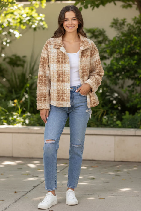 Woman wearing a beige sherpa jacket with a plain background