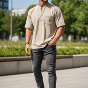 Man wearing a beige short-sleeve shirt with a pocket on a white background