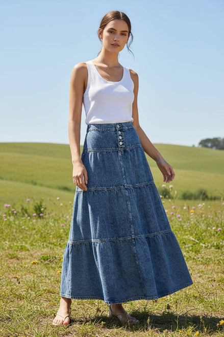 A blue denim tiered maxi skirt with a buttoned waistband, shown on a model 