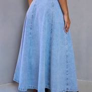 Long denim skirt worn by a person on a plain background