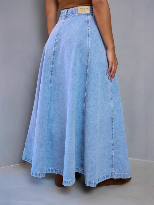 Long denim skirt worn by a person on a plain background