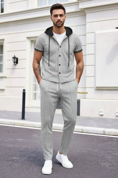A man wearing a light gray two-piece tracksuit with a short-sleeve button-up hoodie and matching drawstring pants, 