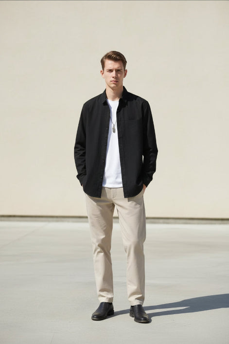 Person wearing a black long-sleeve shirt over a white shirt on a gray background
