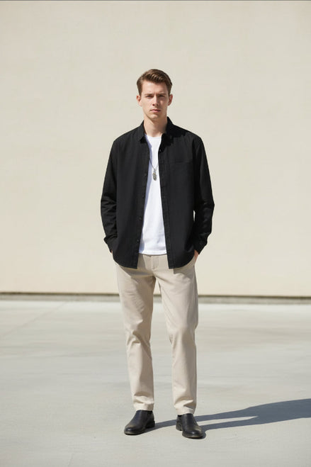Person wearing a black long-sleeve shirt over a white shirt on a gray background