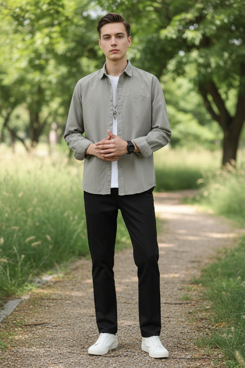 Person wearing a light gray button-up shirt over a white t-shirt on a plain background
