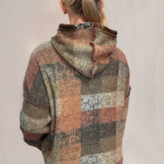 Person wearing a plaid patterned hoodie against a plain background