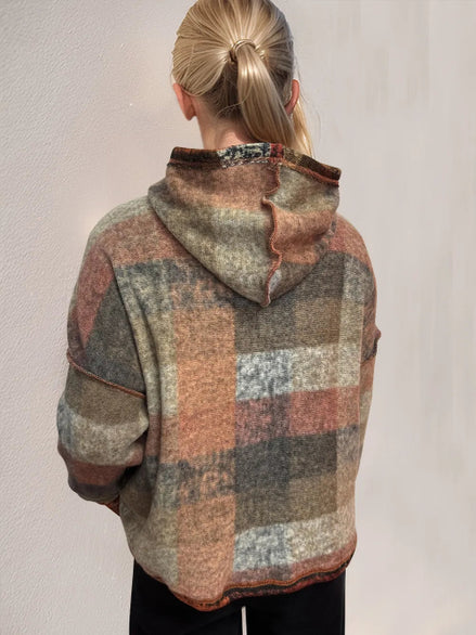 Person wearing a plaid patterned hoodie against a plain background