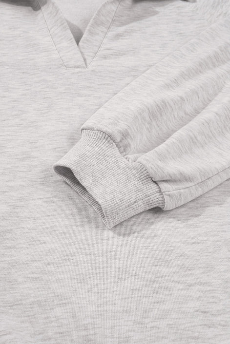 Close-up of a gray sweatshirt with a focus on the sleeve and collar.