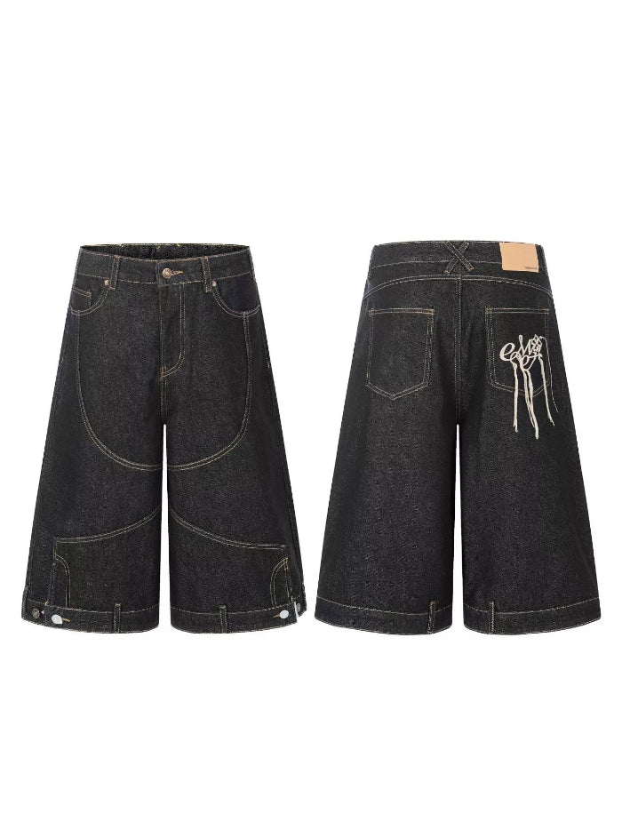 A pair of dark washed denim shorts shown from both the front and back views. The front features a classic five-pocket layout with unique curved pocket details, while the back displays a large decorative white graphic on the back pocket.
