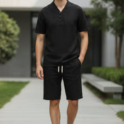 Black outfit with a shirt and pants on hangers against a white background