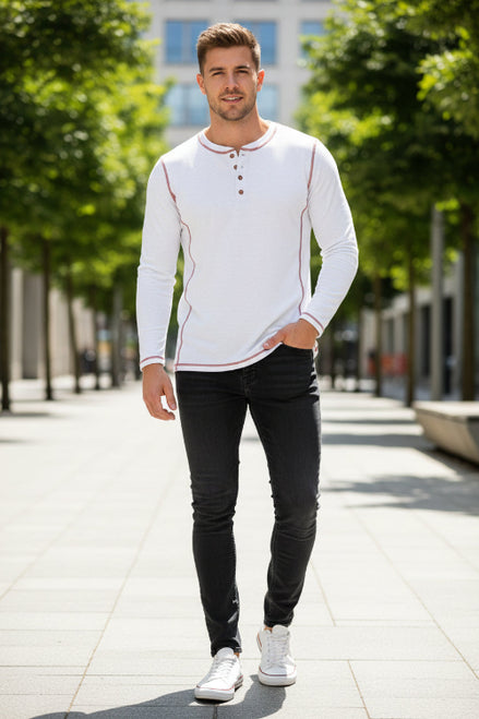 Man wearing a white long-sleeve shirt with red accents and black pants on a city street.