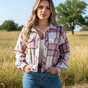 Person wearing a pink and white plaid shirt with blue jeans against a white background