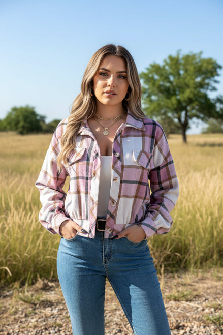 Person wearing a pink and white plaid shirt with blue jeans against a white background