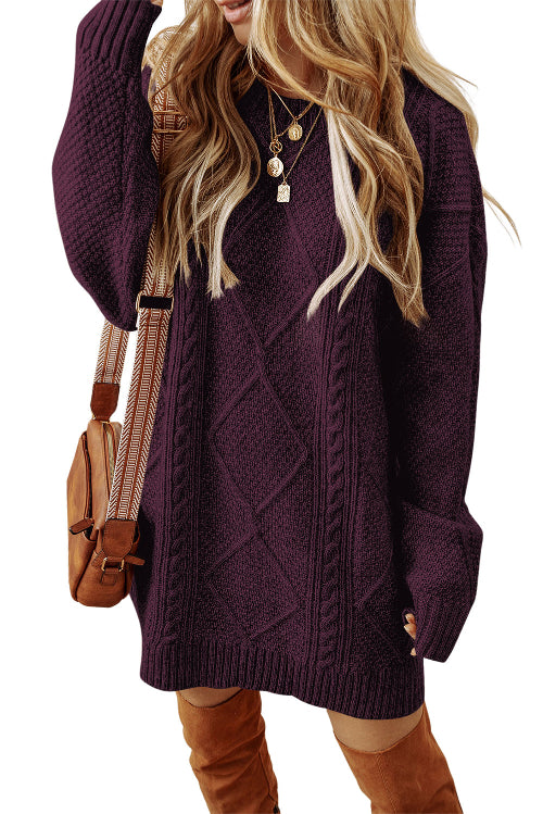 A woman wearing an oversized cable-knit sweater in deep plum purple, styled with brown suede boots and a brown