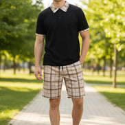 Black polo shirt with plaid collar and beige plaid shorts on a white background