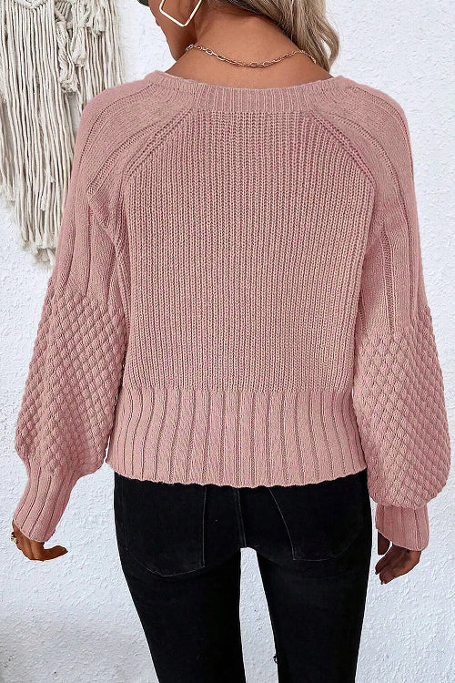 Person wearing a pink knitted sweater against a white background