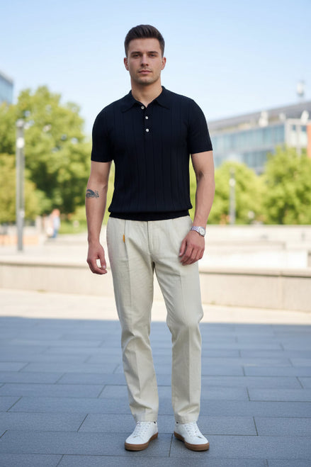 Person wearing a black polo shirt holding a book and a bicycle indoors.