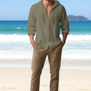 Man wearing a green button-up shirt with a blurred beach background