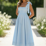 Woman wearing a light blue dress with a bow detail on a plain background