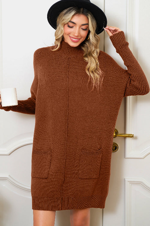 Woman wearing a brown sweater dress with a black hat against a white door background