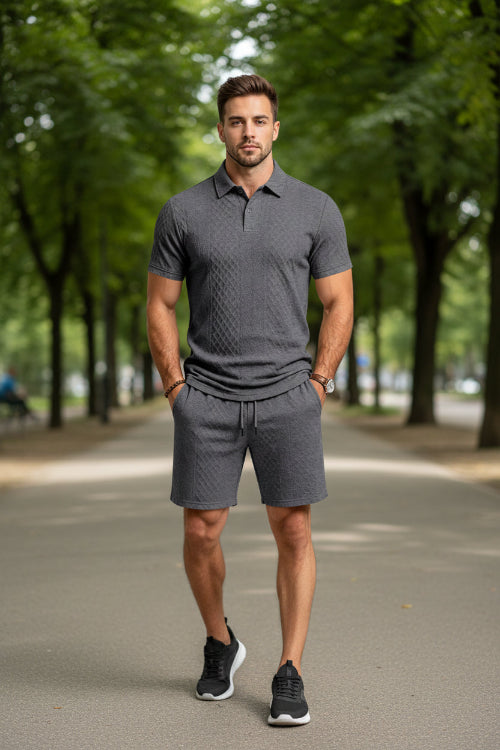 A man wearing a dark gray short-sleeve polo shirt and matching dark gray shorts with a textured diamond pattern,