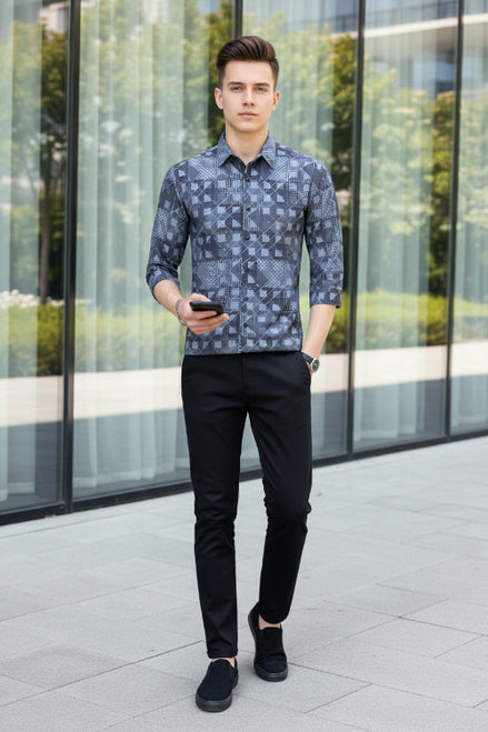 Person wearing a patterned shirt with geometric design, holding a phone.