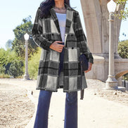 Woman wearing a plaid coat and blue jeans standing outdoors 
