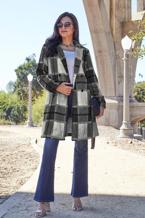 Woman wearing a plaid coat and blue jeans standing outdoors 