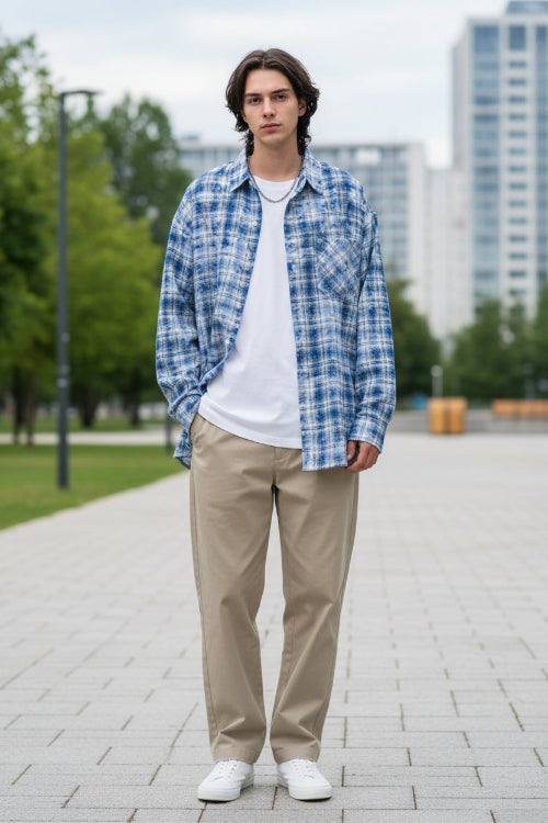 Person wearing a blue and white plaid shirt with arms crossed on a white background