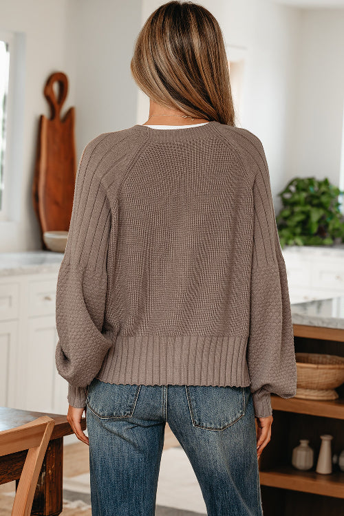 Person wearing a brown sweater and blue jeans in a kitchen setting