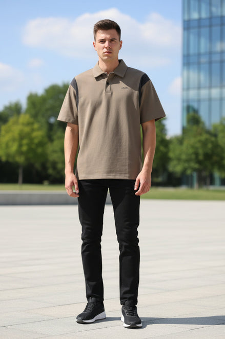 Man wearing a brown polo shirt with black accents and a cap on a light gray background
