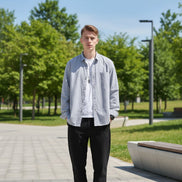 Person wearing a light blue button-up shirt with rolled-up sleeves against a gray background