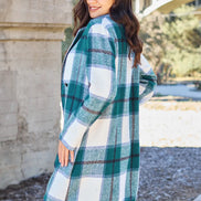 Woman wearing a plaid coat outdoors with trees and a building in the background