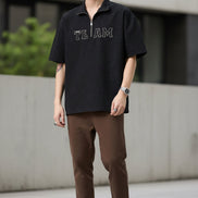 Person wearing a black short-sleeve shirt with 'TEAM' text on a plain background