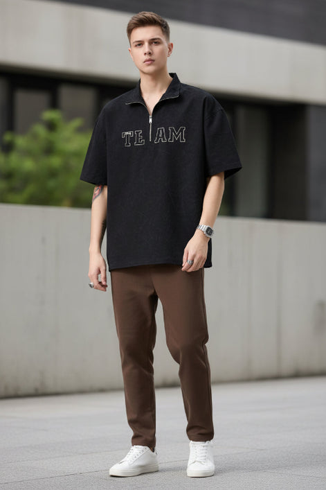 Person wearing a black short-sleeve shirt with 'TEAM' text on a plain background