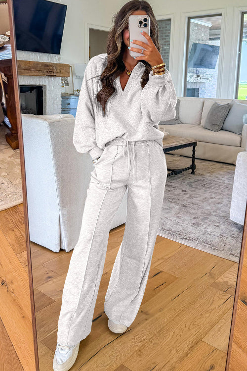 Person wearing a light gray outfit in a living room.