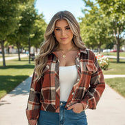 Person wearing a plaid shirt over a white top and blue jeans indoors.