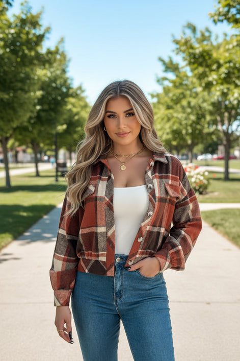 Person wearing a plaid shirt over a white top and blue jeans indoors.