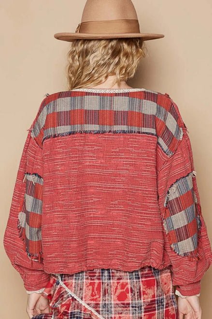 Person wearing a red plaid shirt and hat against a beige background