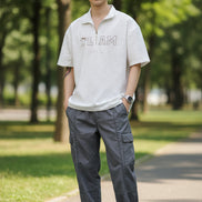 Person wearing a light gray short-sleeve shirt with 'TEAM' text on a plain background