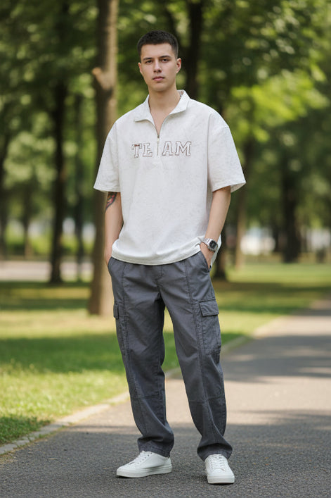Person wearing a light gray short-sleeve shirt with 'TEAM' text on a plain background