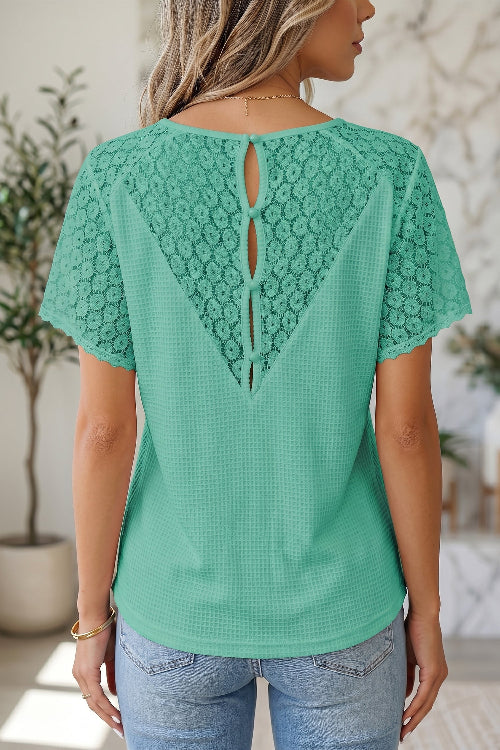 Green lace-back top worn by a person in an indoor setting with plants.