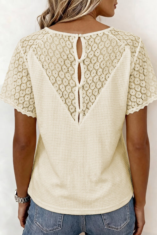 Woman wearing a cream-colored blouse with lace details on a white background